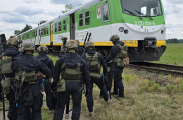 Funkcjonariusze policji w trakcie ćwiczeń pod kryptonimem "Ostrołęka 2025", na tle pojazdu EN71KM.