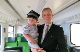 Zdjęcie kierownika pociągu z dzieckiem, które ma założoną rogatywkę 