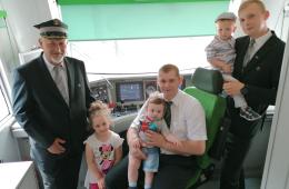 Zdjęcie w kabiny maszynisty pracowników KM (maszyniści KM i kierownik pociągu) z dziećmi 